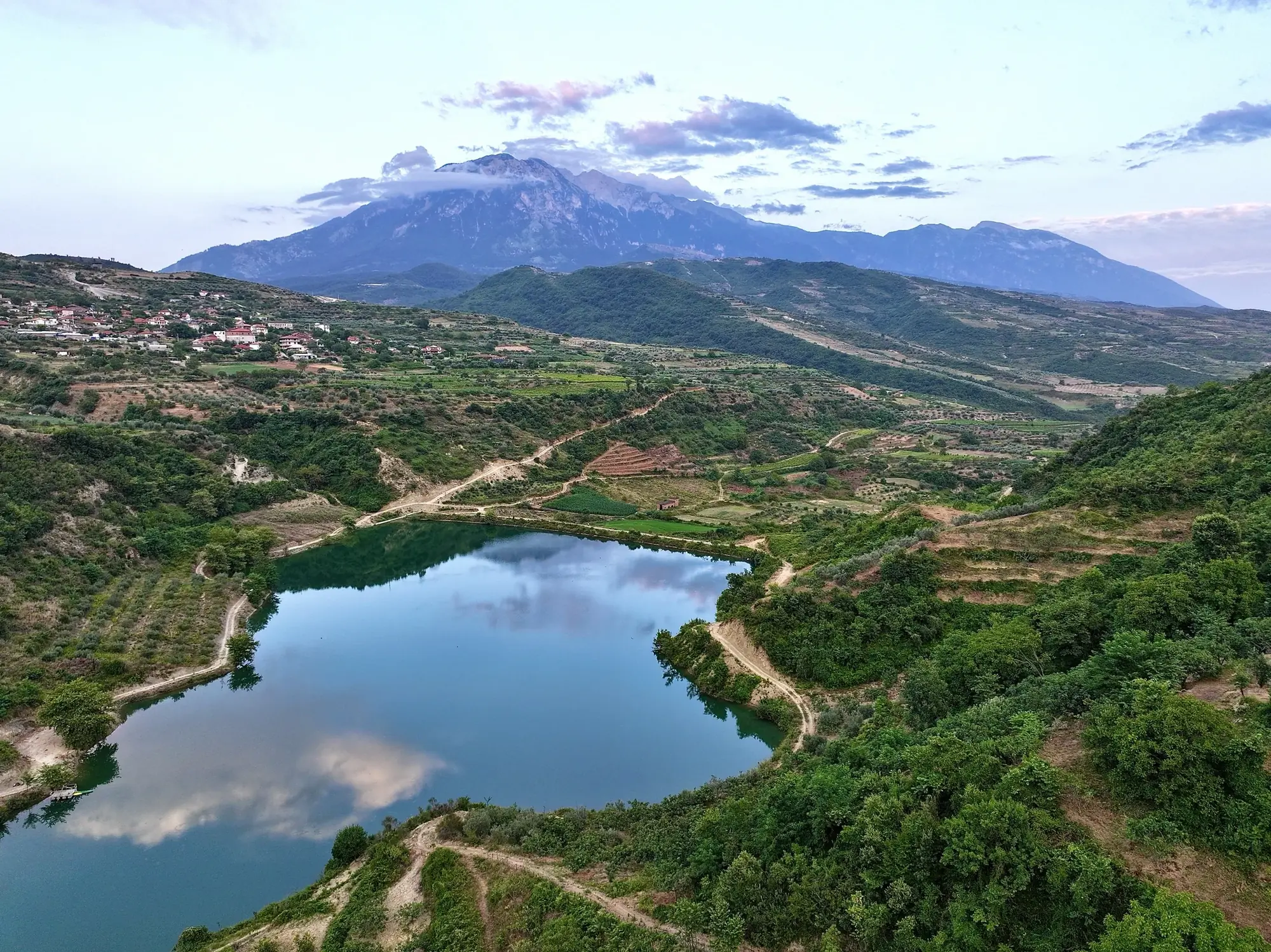 Roshnik lake in the valley below Mount Tomorri, with the village on the hillside