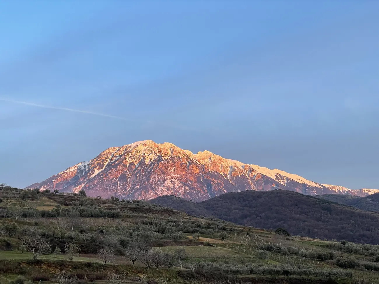 The snow-covered summit ridge of Tomorri glowing pink at sunset